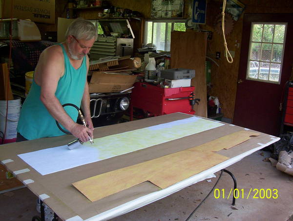 Pleather cut and being sprayed with adhesive.