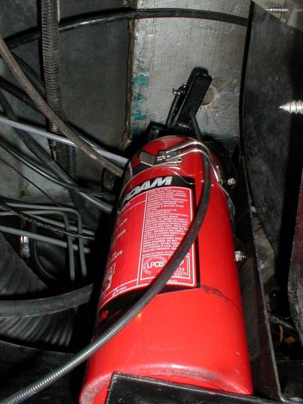 CAREFULLY raise the extinguisher into position and lock the holding strap.